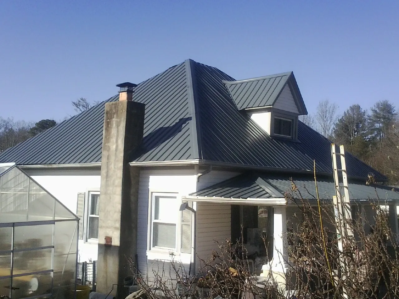 Dark blue standing seam metal roof on a white farmhouse with dormer — Slate & Tile Roof Repair by Roofing Brothers in Pinon Hills