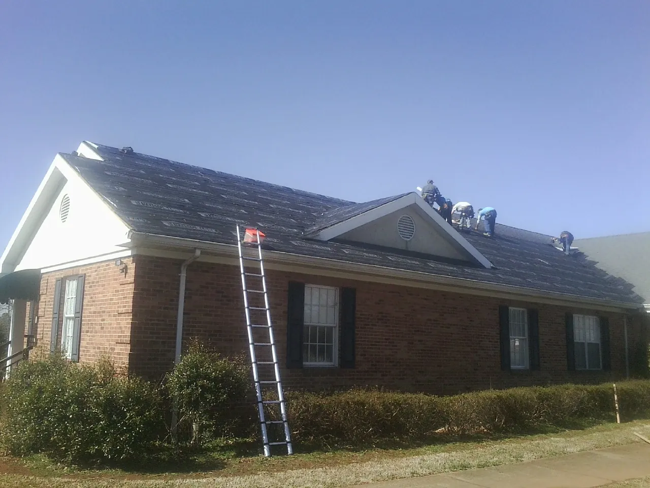 Crew tearing shingles off a brick ranch roof with a ladder set — Metal Roof Repair work by our crew in Pinon Hills