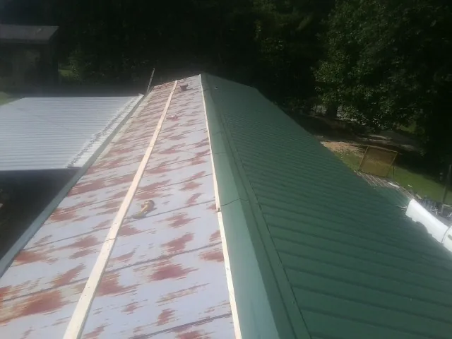 Old rusted panels beside newly installed green metal roofing — Wind Damage Roof Repair by Roofing Brothers in Pinon Hills