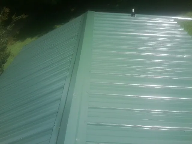 New green metal panels meeting at the ridge of a roof — Flat Roof Repair work by our crew in Pinon Hills