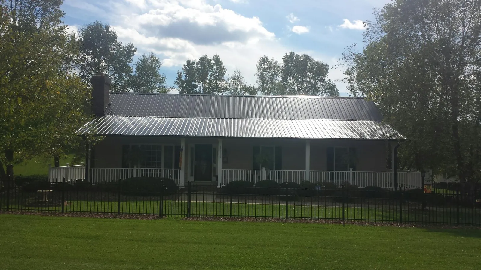 Gray metal roof on a brick ranch with a full width front porch — Gutter Guard Installation work by our crew in Pinon Hills