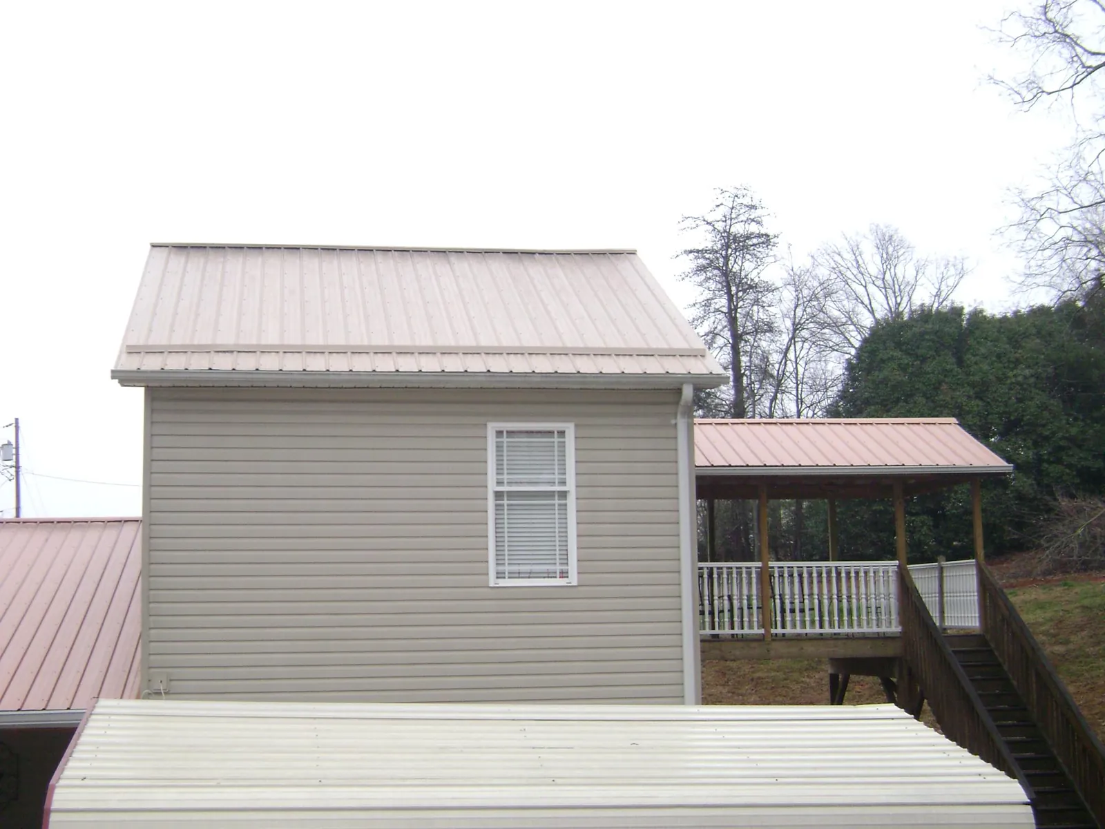 Tan metal roofs on a two story addition and attached porch, from a Roof Replacement job in Pinon Hills