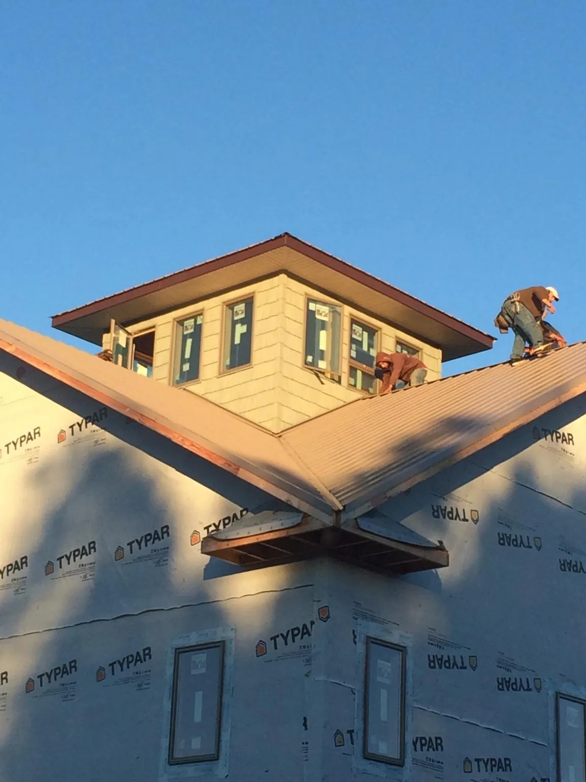 Roofers working around a rooftop cupola on a new metal roof at sunset — Roof Waterproofing in Pinon Hills by Roofing Brothers